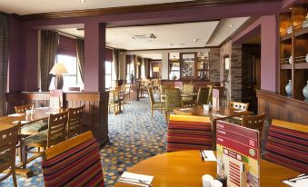 a well - lit dining area in a restaurant , with tables and chairs arranged for guests to enjoy their meal at Premier Inn Liverpool (Tarbock)