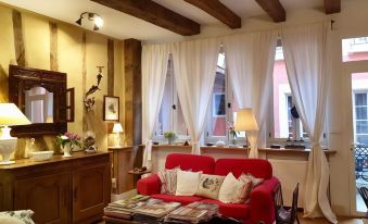 a cozy living room with a red couch , wooden furniture , and a tv mounted on the wall at Ombre Rose