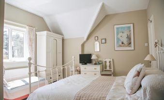 a cozy bedroom with a white bed , a tv on the wall , and a dresser nearby at Yew Tree Farm Cottages Congleton
