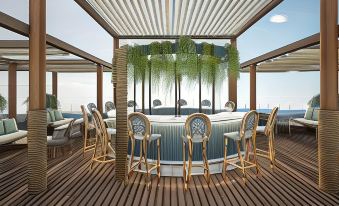 a wooden deck with a bar , umbrellas , and chairs under a thatched roof , overlooking the ocean at Ocean V Hotel