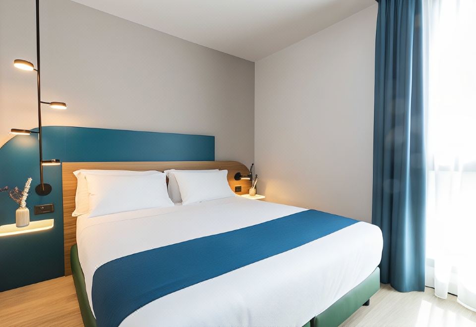 a neatly made bed with white and blue bedding is situated in a hotel room at Belstay Milano Linate