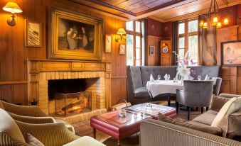 a cozy living room with wooden furniture , including a couch , chairs , and a dining table at Hotel 115