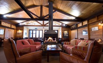 a cozy living room with a fireplace , couches , and chairs arranged in front of the fireplace at The Park Hotel Ruapehu