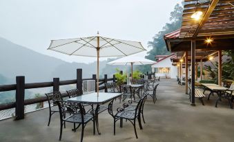 an outdoor dining area with a table , chairs , and umbrellas on a deck overlooking a mountainous landscape at Rainbow Hotel