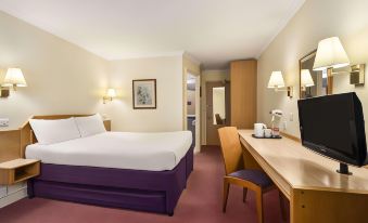 a hotel room with a purple bed , desk , and chairs , as well as a desk and telephone at Super 8 by Wyndham Chester East