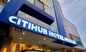 "a tall building with a blue sign that says "" citihub hotel "" in white letters , and several cars parked outside" at Citihub Hotel @Kediri