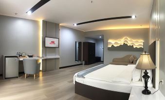 a modern bedroom with a large bed , a desk , and a tv . also a bathroom nearby at Surya Yudha Hotel