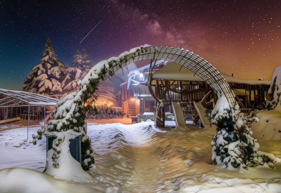 a snowy mountain scene with a wooden structure and a bridge , illuminated by lights at night at VeLa