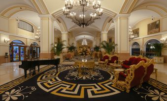 a luxurious hotel lobby with a large grand piano and red chairs in the center , surrounded by ornate decorations at Kremlin Palace