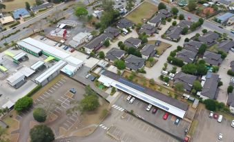 aerial view of a large parking lot with multiple cars and a building in the background at Kallangur Motel