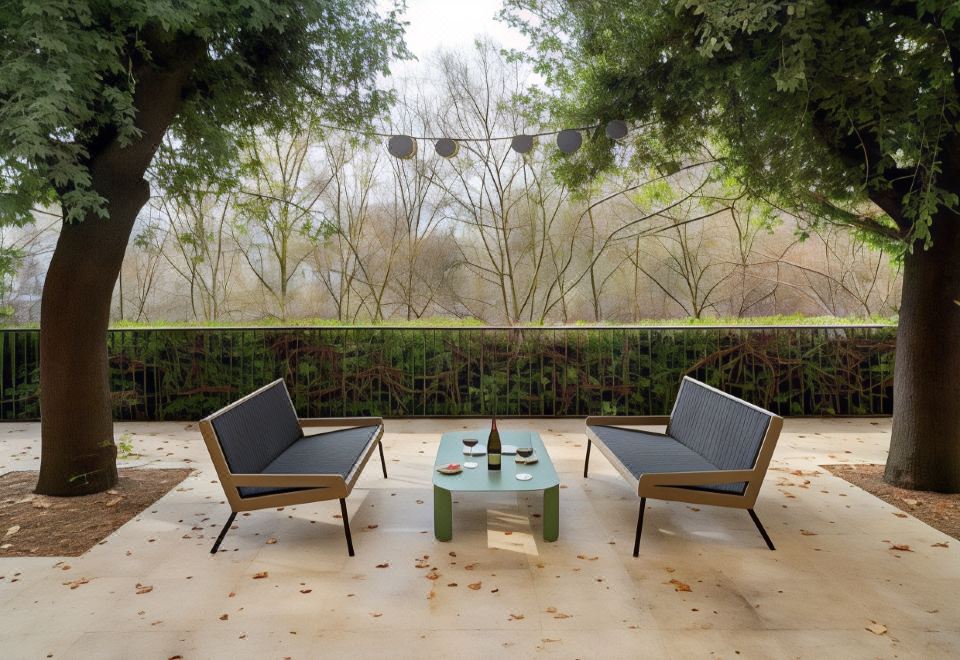 a patio with two chairs and a green table , surrounded by trees and a building at Parador de Leon - San Marcos