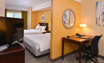a hotel room with two beds , a desk , and a round mirror on the wall at SpringHill Suites Pittsburgh Mills