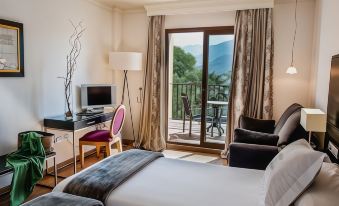 a hotel room with a bed , desk , and chair is shown with a view of the mountains at B Bou Hotel la Vinuela & Spa