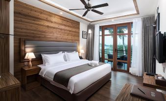 a large bed with a wooden headboard and white linens is in a room with a sliding glass door at Pearl Sands of Maldives