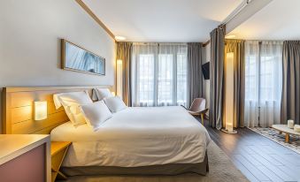 a hotel room with a king - sized bed in the center , surrounded by various pieces of furniture and decorations at Hotel le Morgane