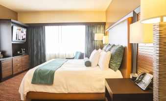 a large bed with white linens and a green blanket is in a hotel room at Akwesasne Mohawk Casino Resort and Players Inn Hotel -Formerly Comfort Inn and Suites Hogansburg NY