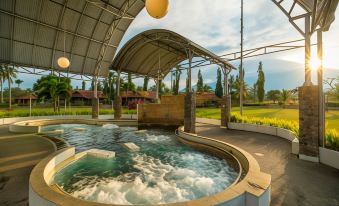 a large outdoor hot tub surrounded by grass and trees , providing a serene and relaxing atmosphere at Horison Tirta Sanita Kuningan