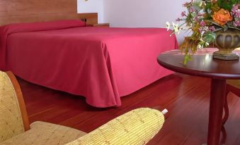 a hotel room with a large bed , a yellow chair , and a vase of flowers on a table at Hotel Valencia