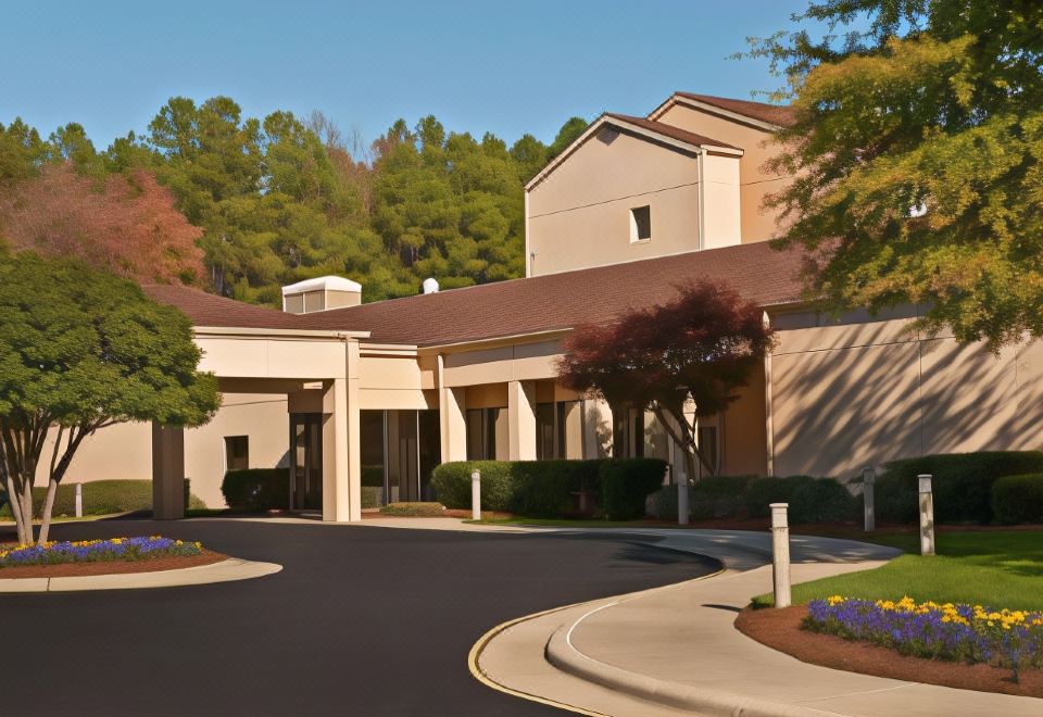 a large , modern building with multiple levels and multiple facades , surrounded by lush greenery and trees at Sonesta Select Raleigh Durham Airport Morrisville