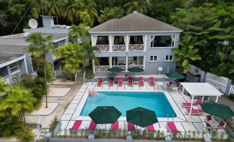 a large pool with red and white chairs and umbrellas in front of a white building at The Palms Resort