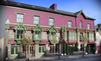 "a pink building with green trim and a red awning has a sign that says "" philz "" on the front" at Castle Hotel Macroom