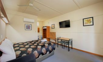 a small hotel room with a bed , a television , a dining table , and a kitchen area at The Terang Motor Inn