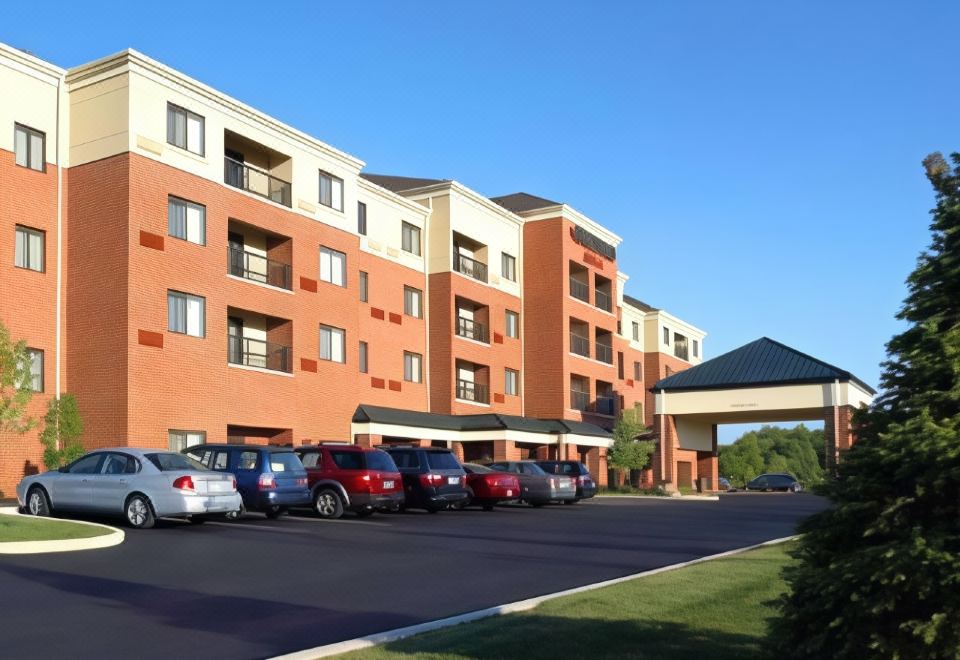 a row of cars parked in front of an apartment building with a blue sky in the background at Courtyard Akron Stow