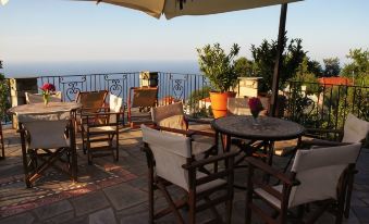 an outdoor dining area with a view of the ocean , surrounded by chairs and umbrellas at Olga