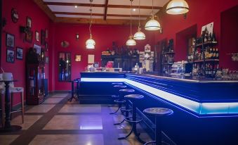 a bar with a long counter and blue lights , surrounded by stools and hanging light fixtures at Balneario de Corconte