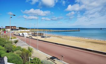 a beach with a pier in the background and palm trees on the left side at La Cremaillere