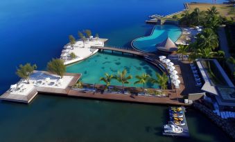 an aerial view of a resort with multiple swimming pools , umbrellas , and lounge chairs surrounded by water at Te Moana Tahiti Resort