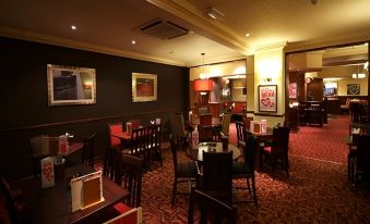 a dining room with a table and chairs , as well as a bar area with stools at Premier Inn Lichfield North East (A38)
