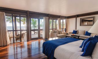 a bedroom with a bed , couch , and sliding glass doors leading to a balcony overlooking the ocean at Sinalei Reef Resort & Spa