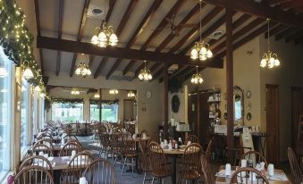 a large , well - lit dining room with wooden tables and chairs arranged for a group of people to enjoy a meal at Woodwards White Mountain Resort, BW Signature Collection
