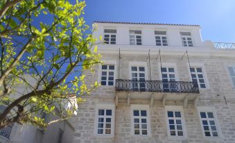 a white building with two balconies and a tree branch in front of it , under a clear blue sky at Habit