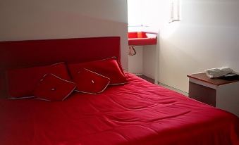 a bed with red sheets and pillows is in a room next to a window at Montesion