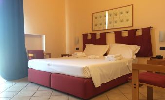 a large bed with white linens and a red headboard is in a room with tile flooring at Hotel Miramare