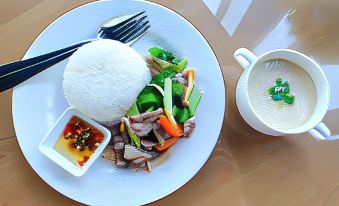 a plate of food with rice , vegetables , and a small bowl of soup next to a small dish of dipping sauce at The Sunnery Ville