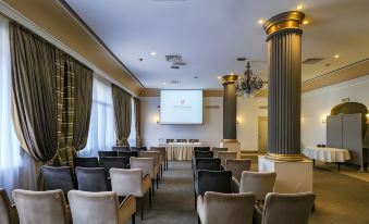 a conference room with rows of chairs arranged in a semicircle and a projector screen on the wall at Majestic Hotel