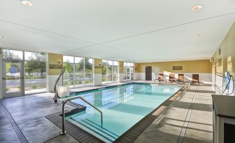 an indoor swimming pool with a large rectangular shape and multiple lanes , surrounded by lounge chairs at Hyatt Place Fresno