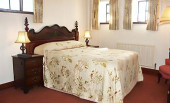 a large bed with a floral comforter is situated between two windows in a bedroom at The Stanley Arms