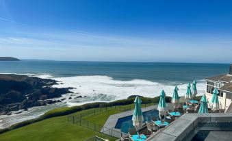 a balcony overlooking the ocean , with several lounge chairs and umbrellas placed on the deck at Watersmeet Hotel