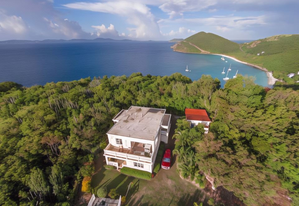 aerial view of a house surrounded by trees , with a body of water in the background at Ocean View Villas