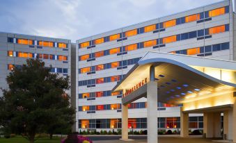 a modern hotel building with an orange roof , surrounded by trees and flowers , under a blue sky at Delta Hotels Woodbridge