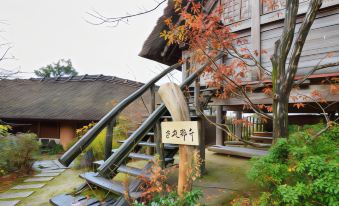 a traditional japanese wooden building with a thatched roof and wooden stairs leading up to it , surrounded by autumn leaves at Shouen