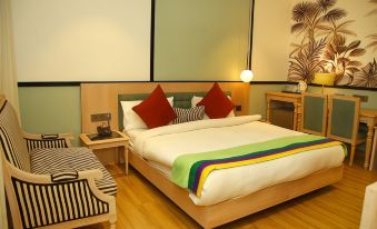 a large bed with a white and green blanket is in a room with wooden floors at Amara Hotel