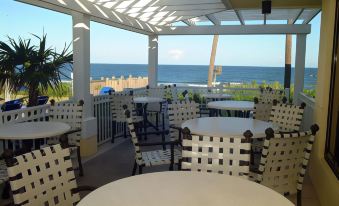 a rooftop patio with white chairs and tables overlooking the ocean , creating a relaxing atmosphere at Delray Sands Resort