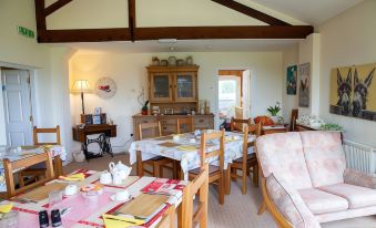 a dining room with a table set for breakfast , surrounded by chairs and a couch at Higher Farm
