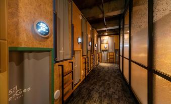 In a long hallway, there are doors and windows on the walls, as well as an empty room beside it at EeGee Stay Kamata