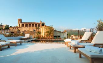 From the rooftop, there is a view of an outdoor patio adorned with chairs and tables at Petit Hotel Forn NOU